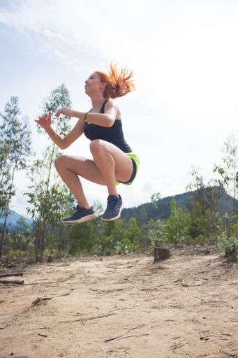 A vertical shot of a young female working out outdoors at daytime