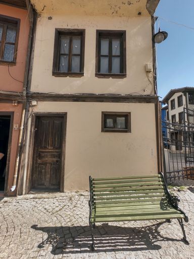 A vertical shot of a bench in front of a building on a sunny day, Eskisehir, Turkey