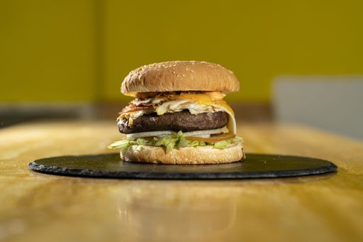 A closeup shot of a burger on a black round board on a wooden table