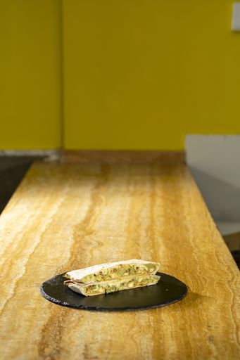 A vertical closeup shot of quesadilla on a black round board on a wooden table