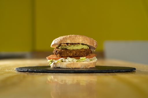 A closeup shot of a burger on a black round board on a wooden table