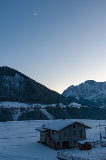 A vertical shot of a small house in the snowy mountains of Schilpario, Italy