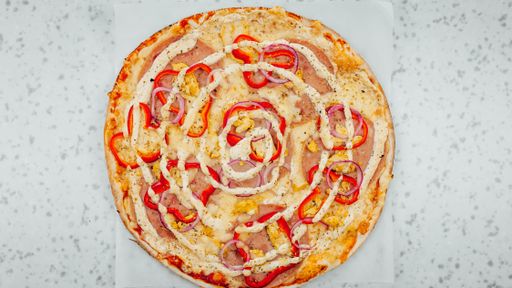 A top view of ham and onion pizza with red bell pepper and sauce