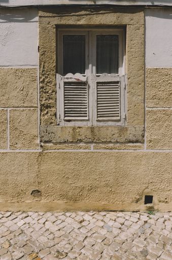 A vertical shot of an old broken window of an abandoned building