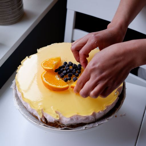 A closeup shot of a female decorating a lemon cheesecake