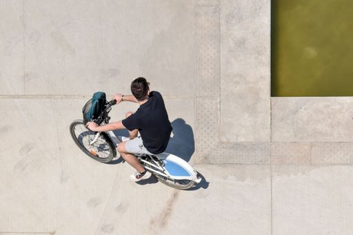 A high-angle view of a young boy on a bicycle outside the Stavros Niarchos Foundation Cultural Center