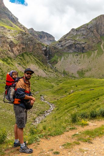 A young man in the mountain trekking with his son in the backpack