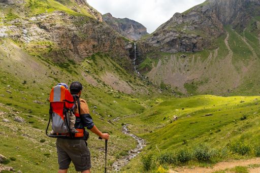 A young man in the mountain trekking with his son in the backpack