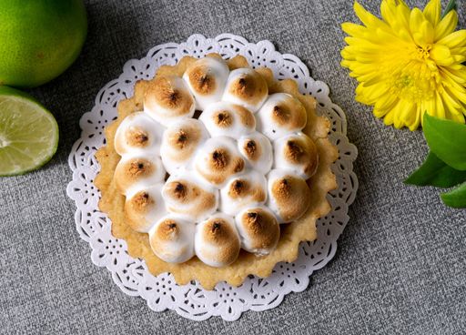 An overhead shot of a biscuit cake and limes on a table with gray cover