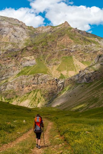 A young woman in the mountain trekking with her son in the backpack