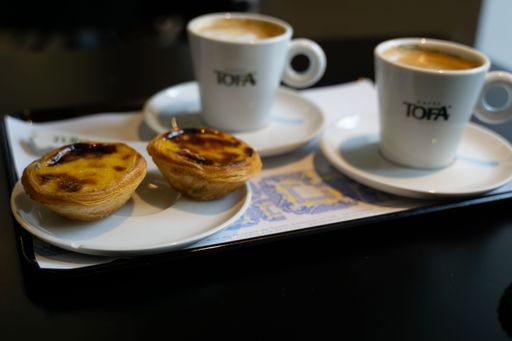 A plate with pastel de nata tart and two cups of coffee in Lisbon, Portugal