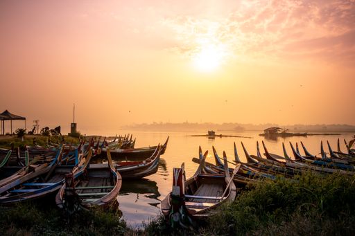 Old wooden boats near the U Bein Bridge during a beautiful sunset in Mandalay, Myanmar