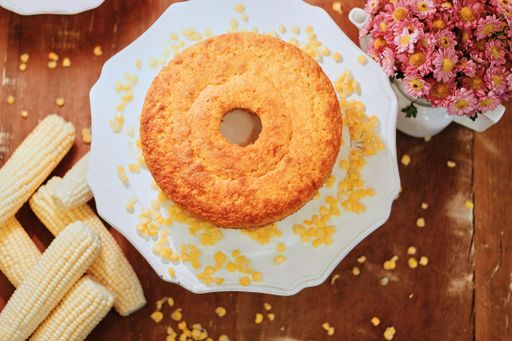 A top view of a delicious homemade cake with corns and pink flowers on a wooden table