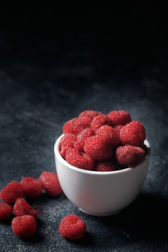 A closeup shot of the delicious raspberries in the white bowl