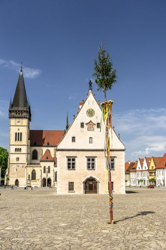 The image shows the famous town square with the church and town hall and a May pole in the center
