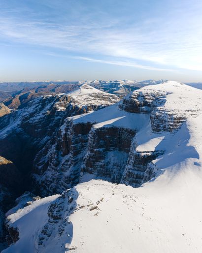 A vertical landscape shot of beautiful mountains covered in snow on a sunny day