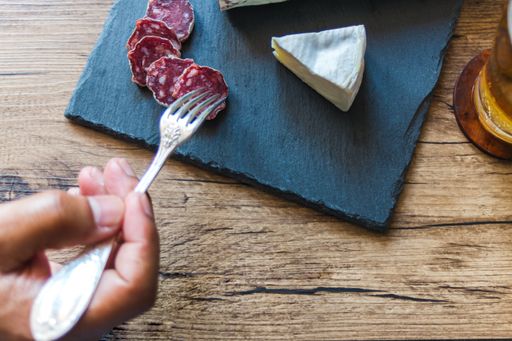 A closeup shot of brie cheese and smoked sausage on a board