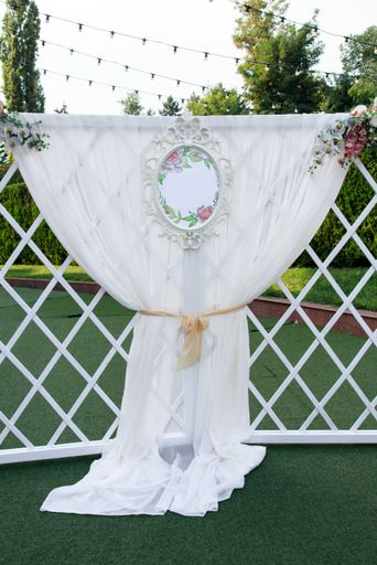 A vertical shot of a decorated wedding curtain hanging on a white fence in the park