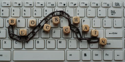 The word 'Blockchain' made with wooden beads with English letters on a white computer keyboard
