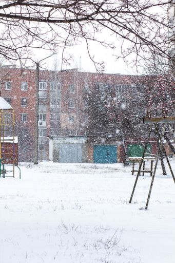 A vertical shot of a red building and beautiful snowflakes falling down and covering everything in white