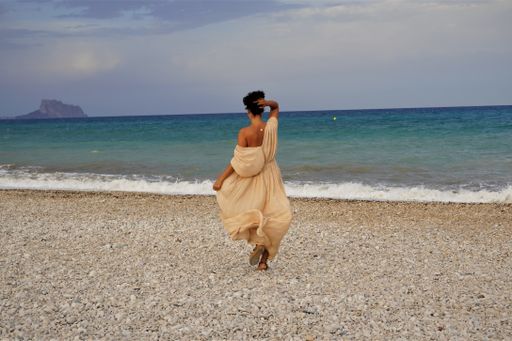A woman standing on a beach with pebbles