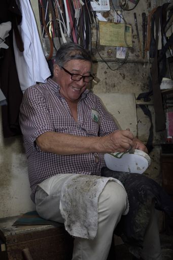 Mature Latino male shoemaker working at his shoe kiosk in Medellin