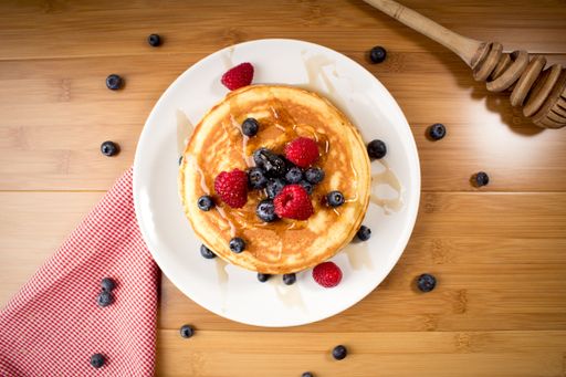An overhead shot of freshly baked pancakes with fresh berries on top