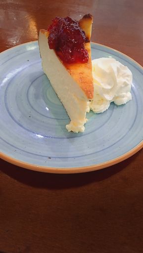 A closeup shot of strawberry cheesecake with whip cream  isolated on  a blue plate