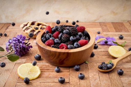 A closeup shot of a wooden bowl of fresh berries on a wooden table in a beautiful set