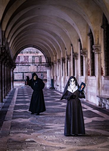 A vertical shot of people wearing religious costumes standing in an old building