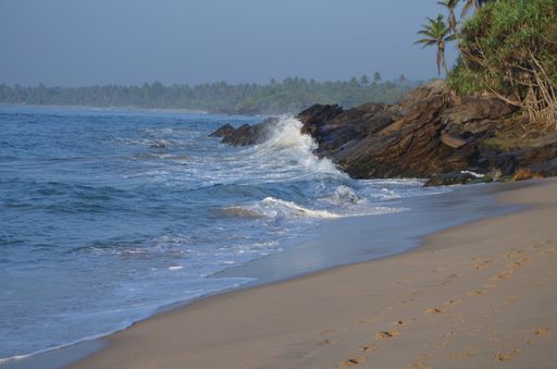 A beautiful scenery of rock formations on the beach with splashing sea waves