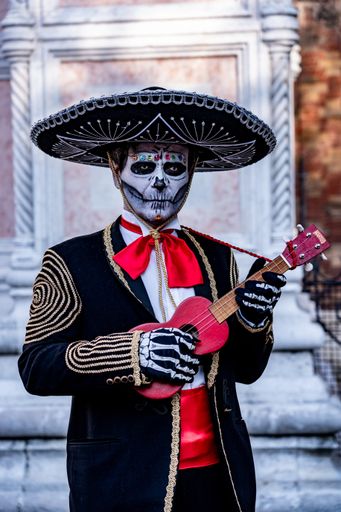 A vertical shot of a male wearing a skeleton costume holding a ukulele