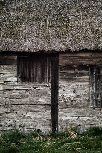 A vertical shot of a wooden building wall in a countryside