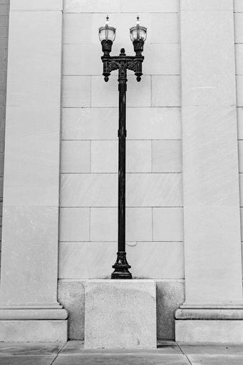 A black antique light post near a white wall