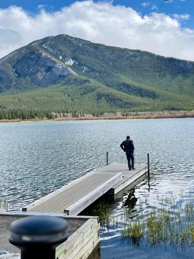 A Caucasian male standing on the edge of a dock on Lake Minnewanka in Banff National Park, Canada