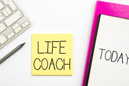 A colorful illustration of a keyboard, glasses, a notebook and a note with life coach text on it