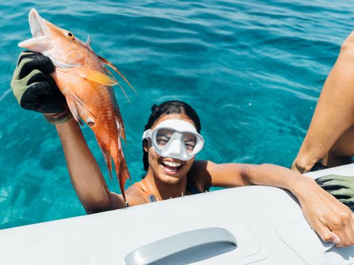 An African American woman smiling holding up a fish caught spearfishing in the Bahamas
