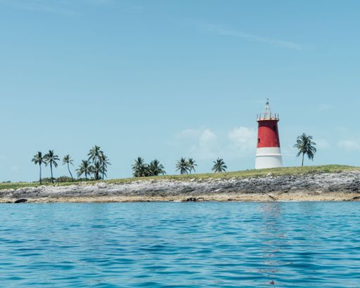 A lighthouse and palm trees on a small island in the Bahamas
