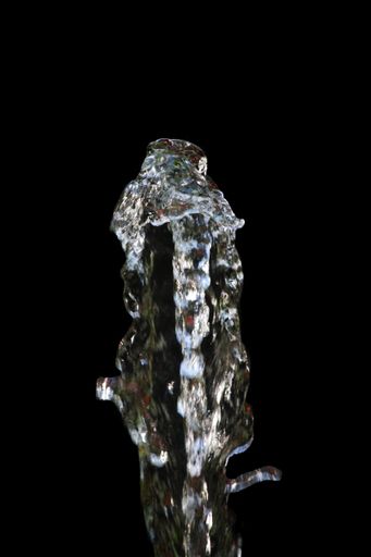 A vertical closeup shot of crystal clear water splashes on a black background