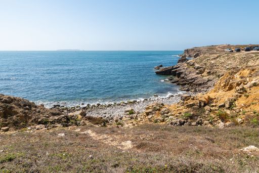 A small beach on the Islet of Papo in Peniche with a calm dark blue sea in Leiria, Portugal