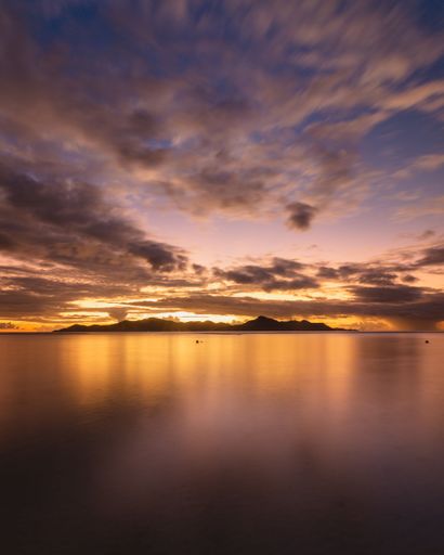 A vertical shot of a magnificent landscape of a sea with the sunset reflection on it