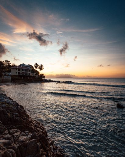 A gorgeous tropical landscape with silhouettes of palm trees by the sea under a colorful sky at sunset