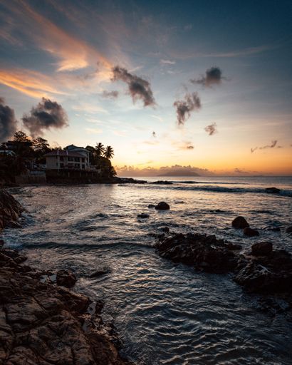 A gorgeous tropical landscape with silhouettes of palm trees by the sea under a colorful sky at sunset