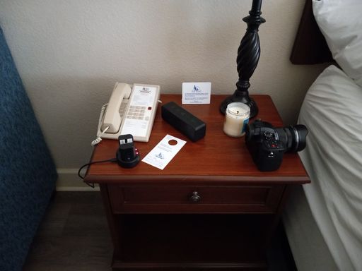 A black photo camera on the hotel bedside table with phone and candle