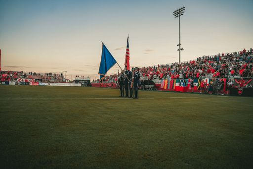 Troops marching with flags in a stadium at a football game