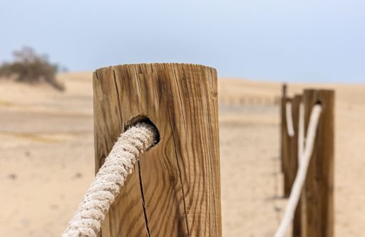 A log fence in a sandy shore on a sunny morning