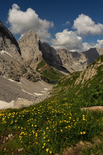 A vertical shot of the Volaia Pass slopes covered in lush grass with cloudy blue sky in the background