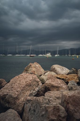 The rows of blue anchored boats in Lake Garda, Italy with rocks in the foreground