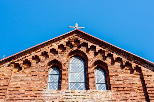 A low angle shot of a church roof with a cross on the top