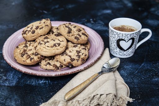 A plate of fresh cookies with a cup of coffee on a kitchen table